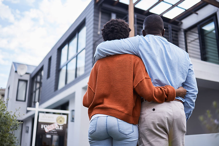 Couple looking at home with sold sign