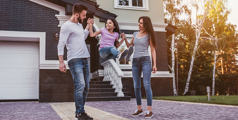 Family swinging child outside in front of house