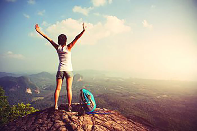 female hiker standing on top of peak