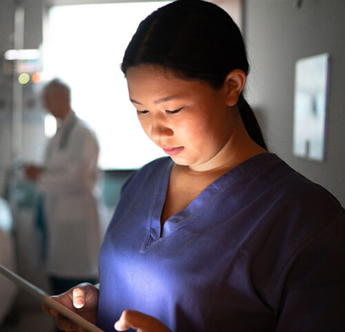 Female Nurse Looking at Tablet in Room