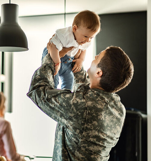 Military Man Holding Baby at Home