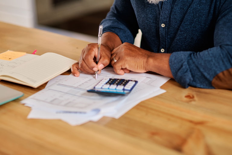 A man doing paperwork with a calculator.