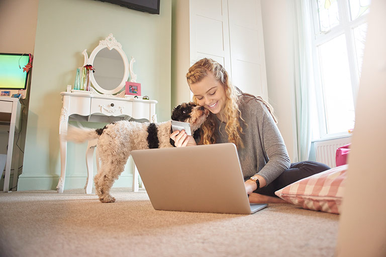 Teen girl with laptop and dog holding credit card