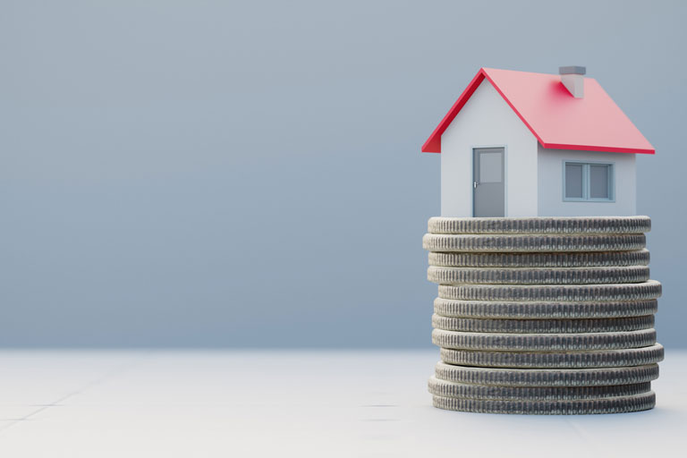 A miniature house on top of a stack of quarters.