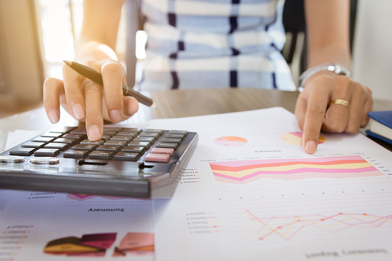 Cropped image of woman using calculator with budgeting paperwork