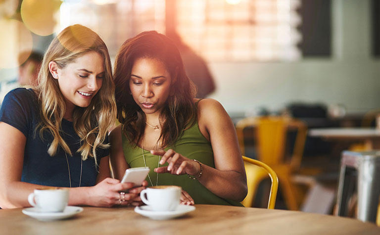 Women in coffee shop looking at mobile phone