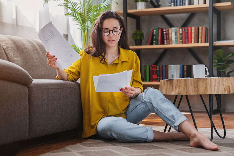 Young woman in living room reviewing papers