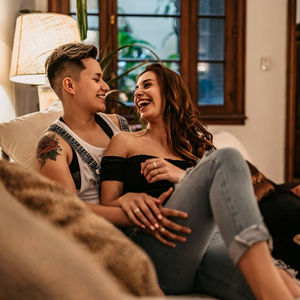 Couple together on the couch laughing and smiling
