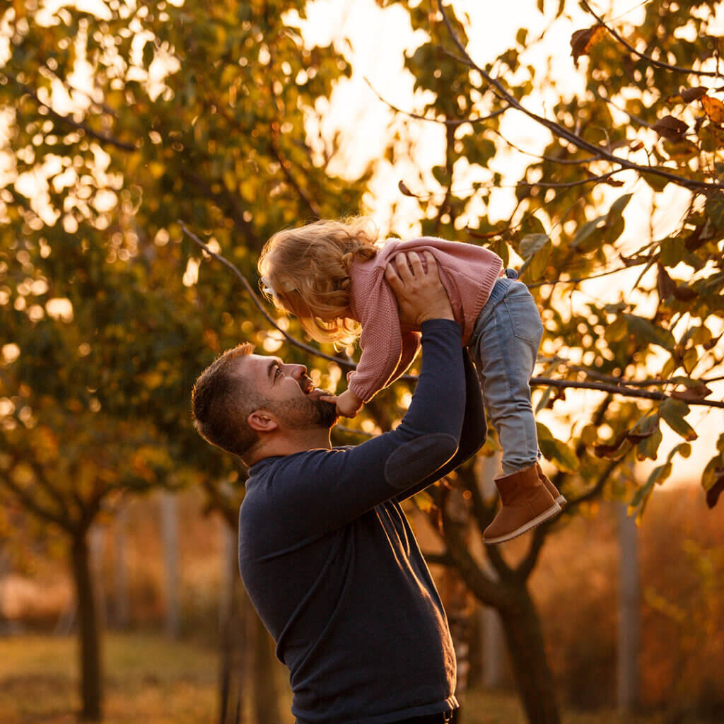 Dad holding daughter up outside