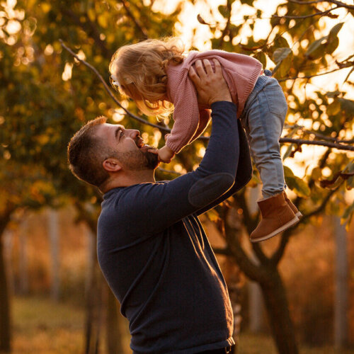 Dad holding daughter up outside