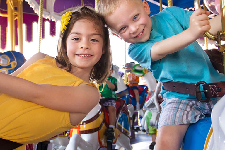 A boy and a girl riding a merry-go-round,
