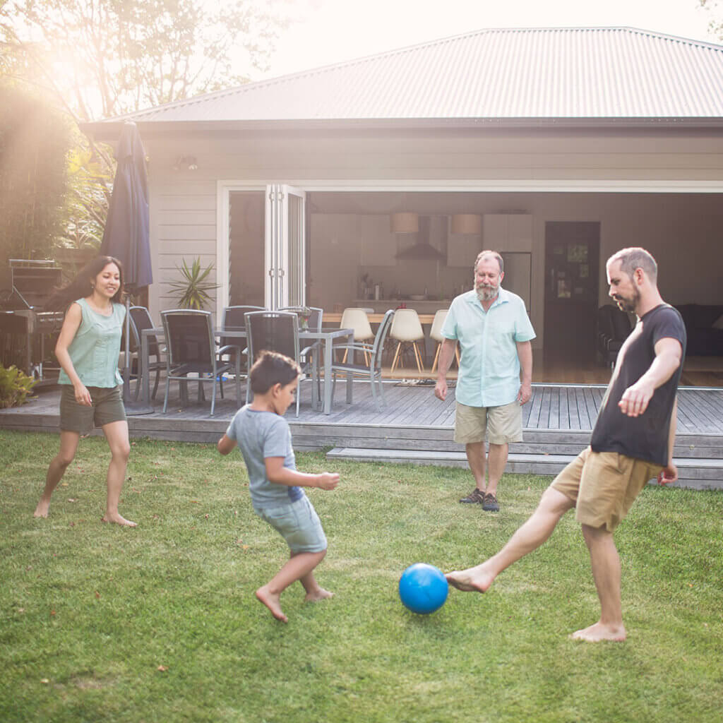 Family playing soccer outside in backyard