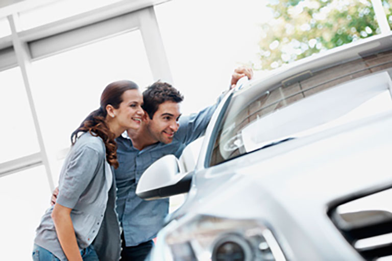 man and woman look inside luxury car