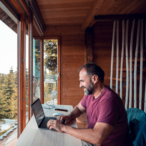 Man using his laptop in a mountain home