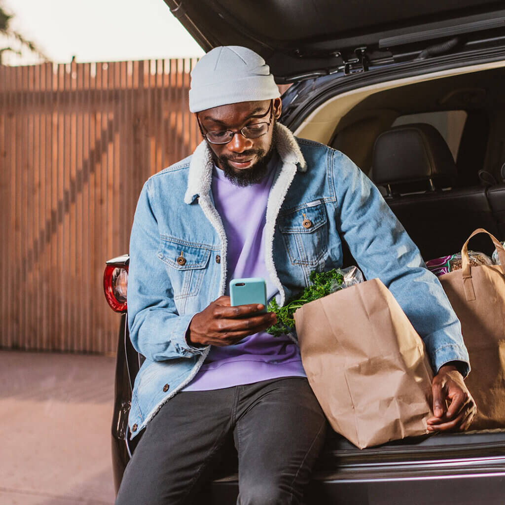 Man on smartphone with groceries