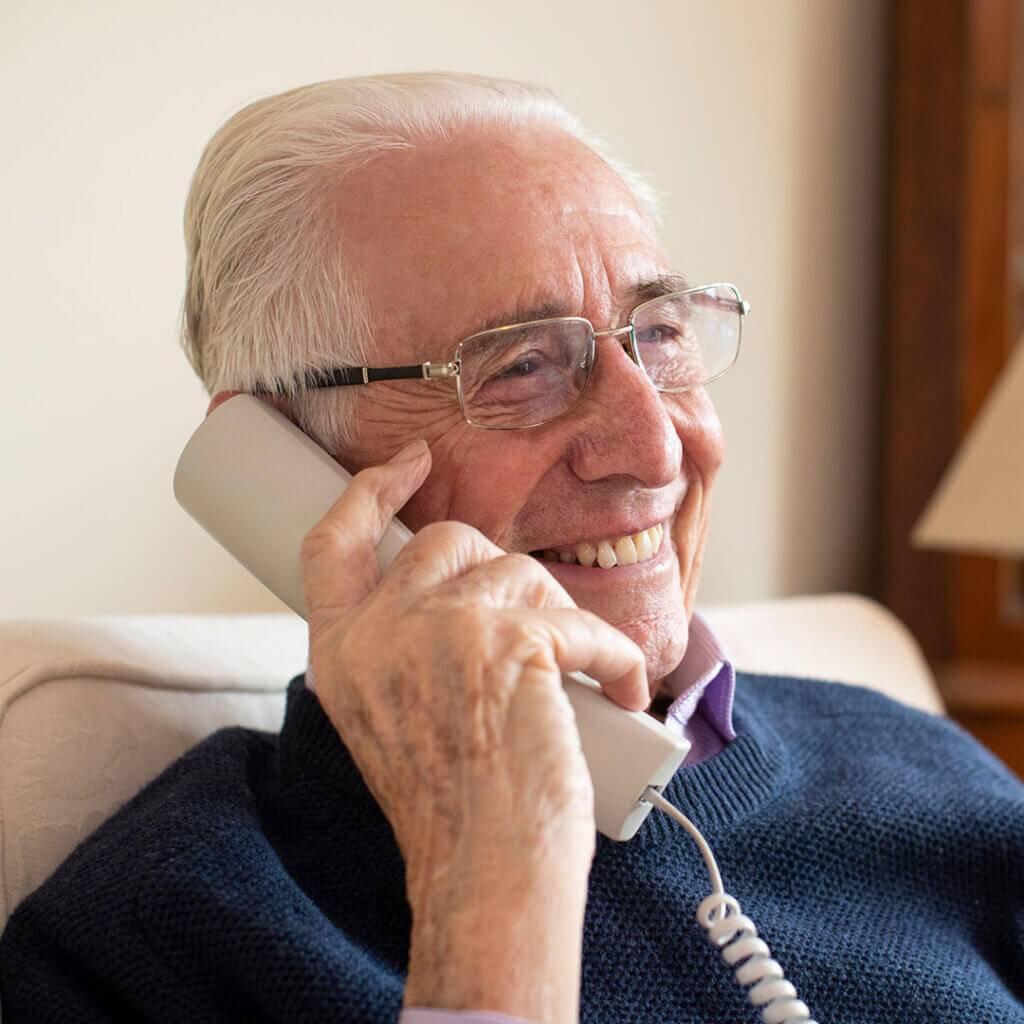 Older man talking on a landline phone