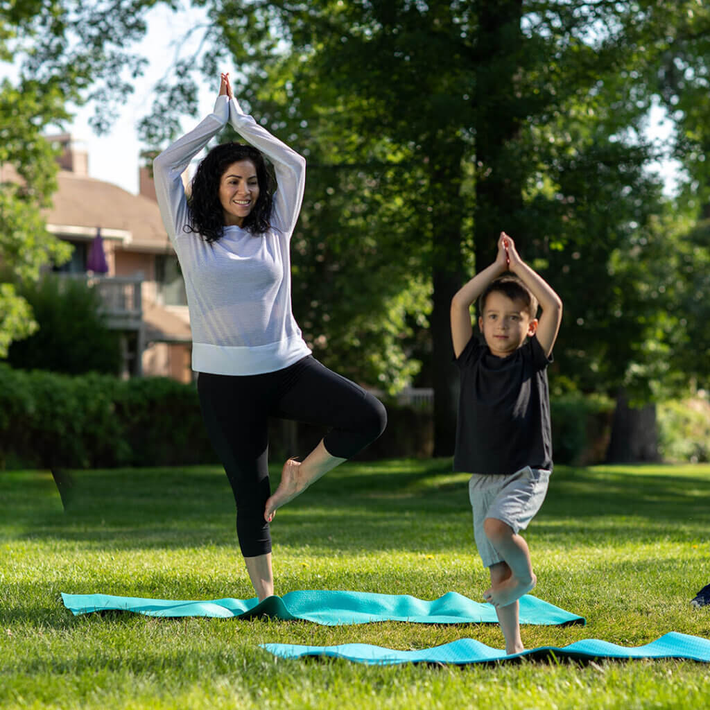 A mom with her son doing yoga outside representing peace from financial coaching