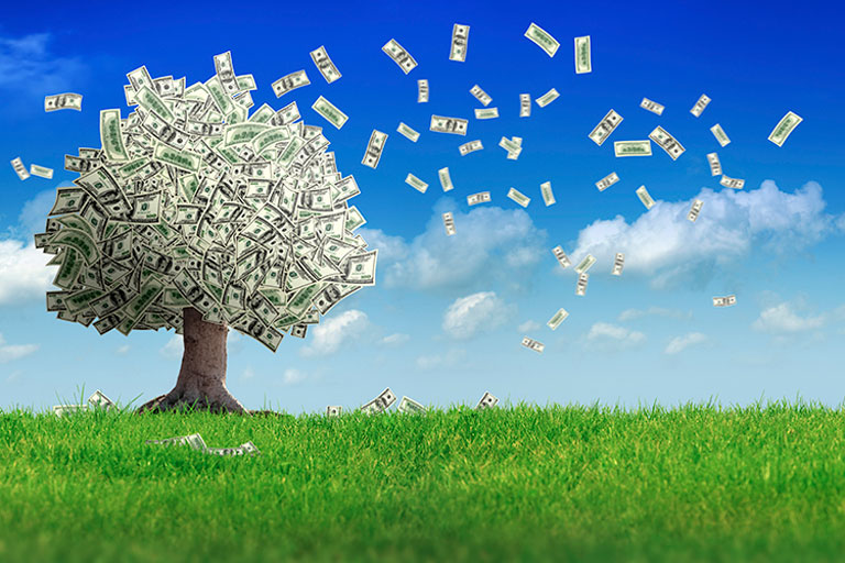 A tree with dollars instead of leaves blowing bills in the wind in a grassy field.