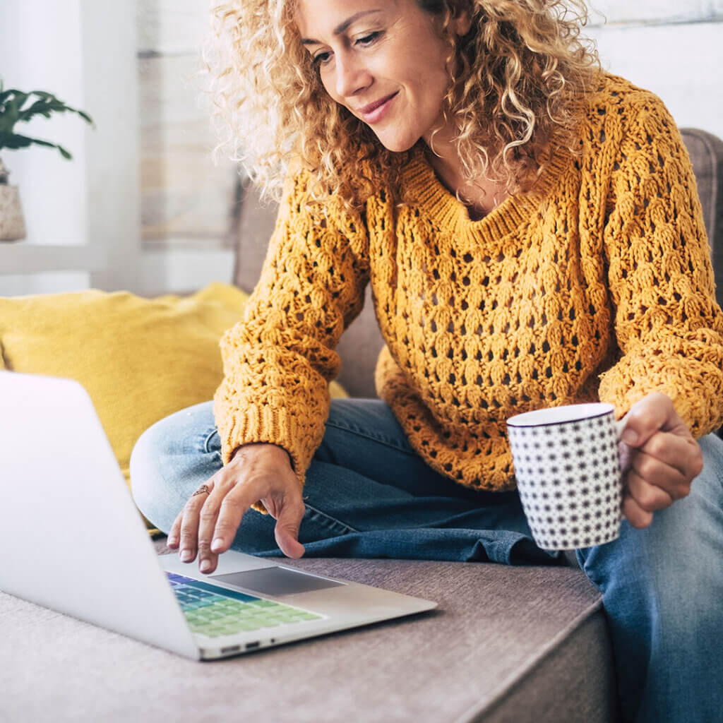 Woman holding coffee while using laptop