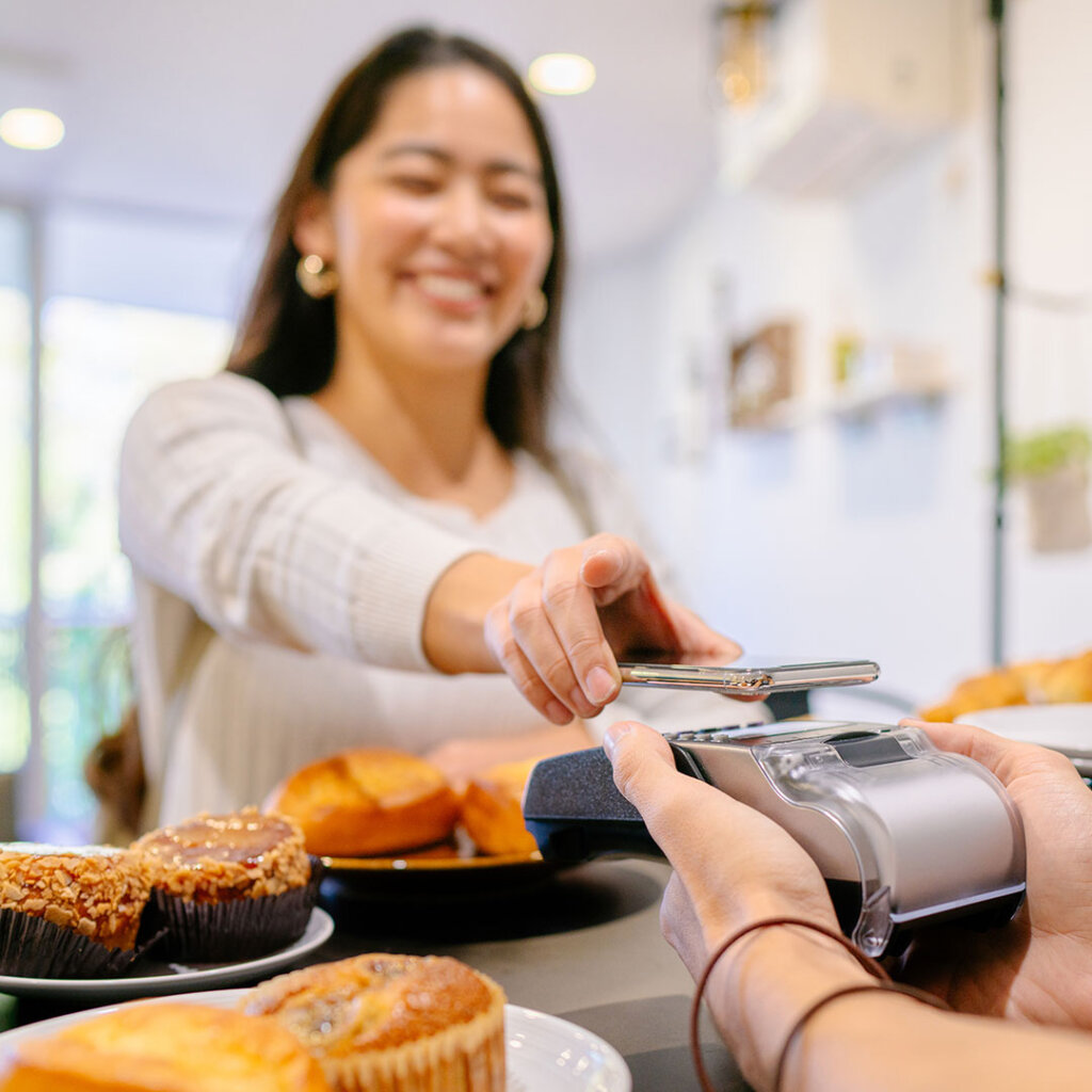 Woman making a mobile payment at a bakery
