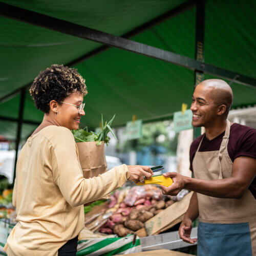 Woman doing mobile payment with a street produce vendor