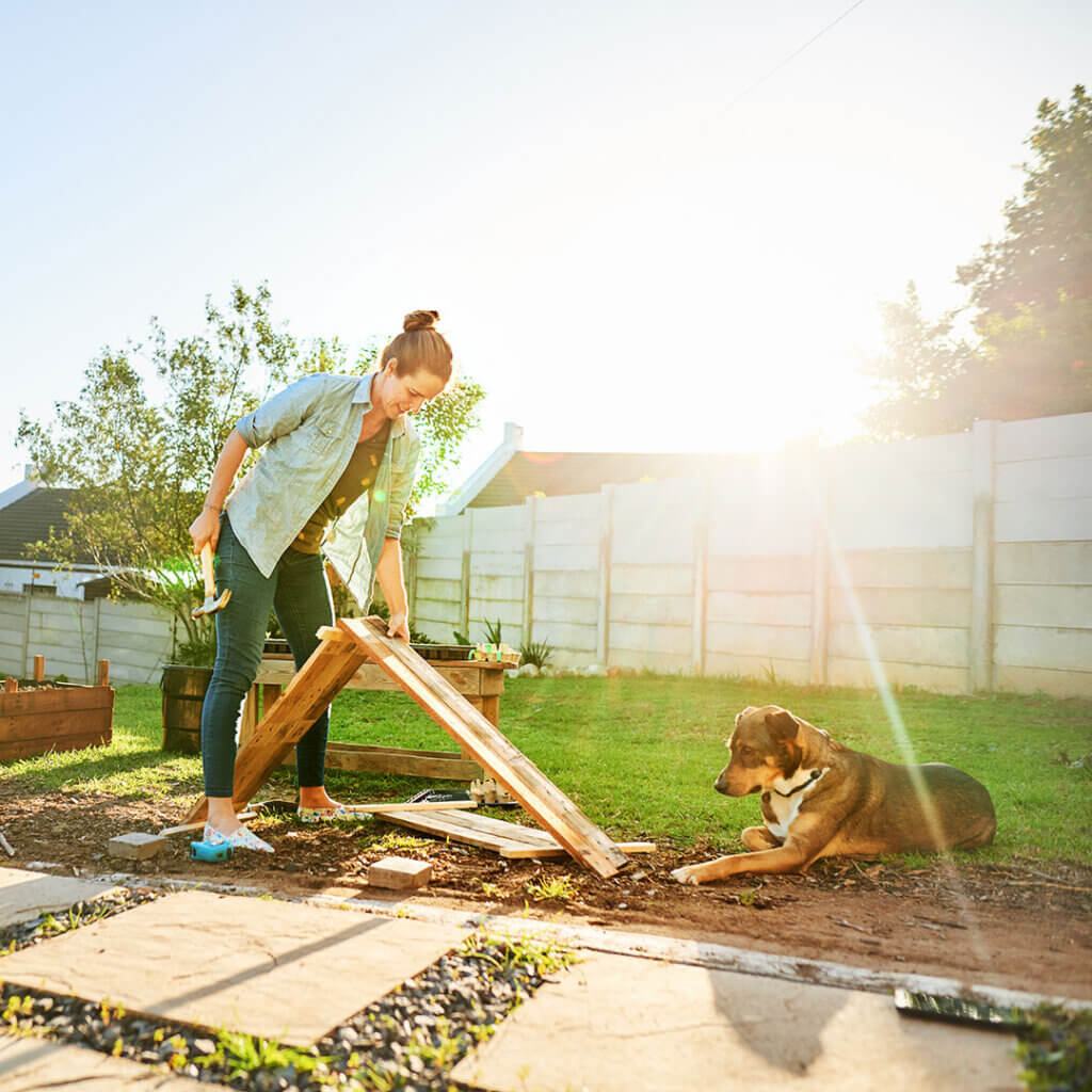 Woman outside working on garden with dog