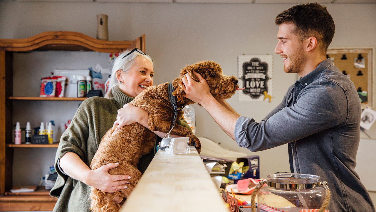 Small business employee receiving licks from customer's dog
