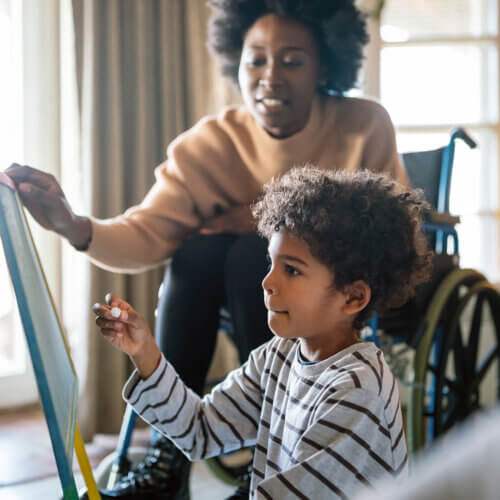 Mom in a wheelchair helping her son with a chalk board