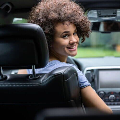 young woman driver in a car smiling