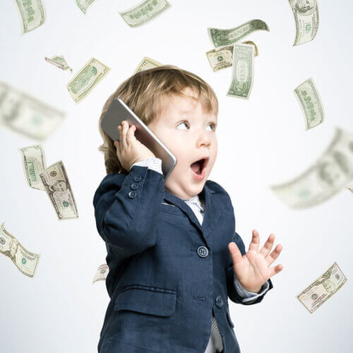 Young boy in a suit holding a phone with money flying around