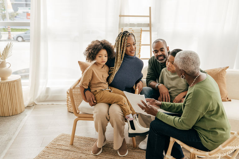 A family sitting down with a grandmother explaining legal documents to her family. Open discussion is a good way to help younger generations manage inheritance.