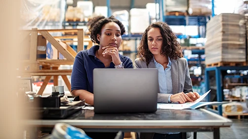 Two manufacturing woman business owners looking at a laptop together