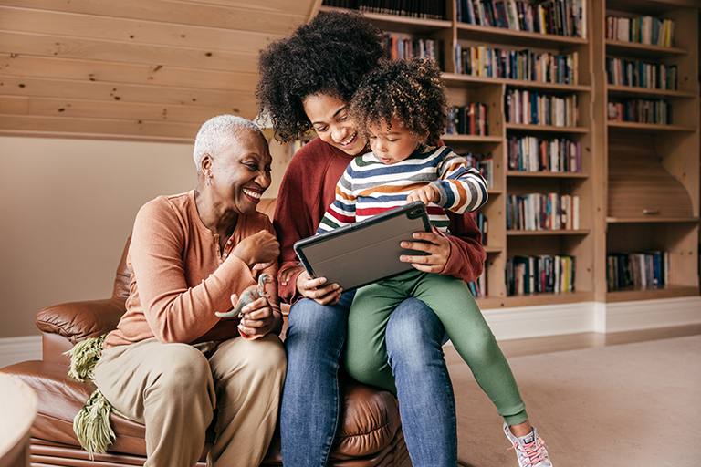 Three generation family sitting with tablet and laughing together