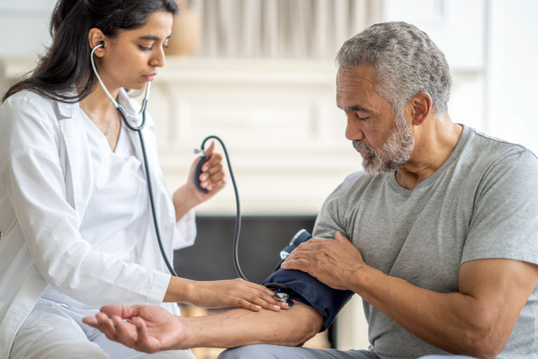 A female doctor performs a blood pressure test on an older man. These types of medical tests aren’t needed with a no medical exam life insurance policy.