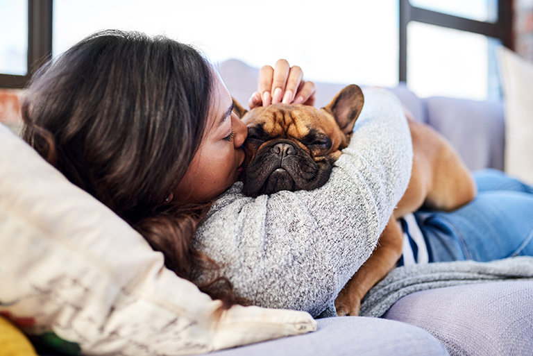 Shot of a young woman relaxing with her dog who is covered with pet insurance