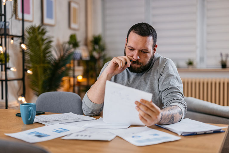 A man looking at a sheet of paper considering if a debt consolidation loan is right for him.
