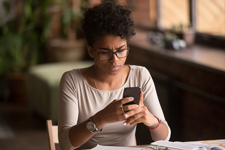 Young woman looking at her phone with concern. If you think you are the victim of P2P Scams it's best to slow down and follow these tips.