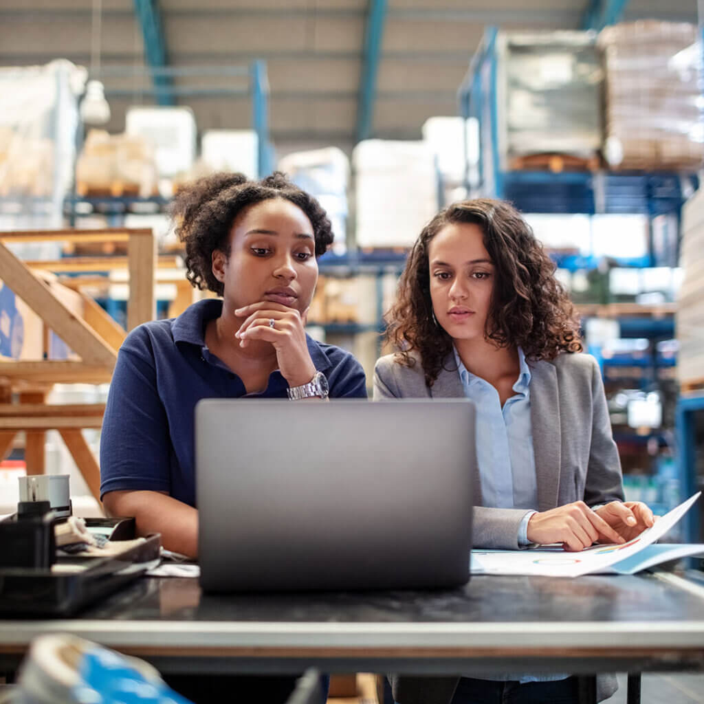 Two warehouse business owners looking concerned at a laptop because of payment fraud