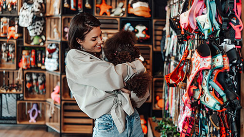 Woman with her dog using her rewards checking account to shop at a pet store